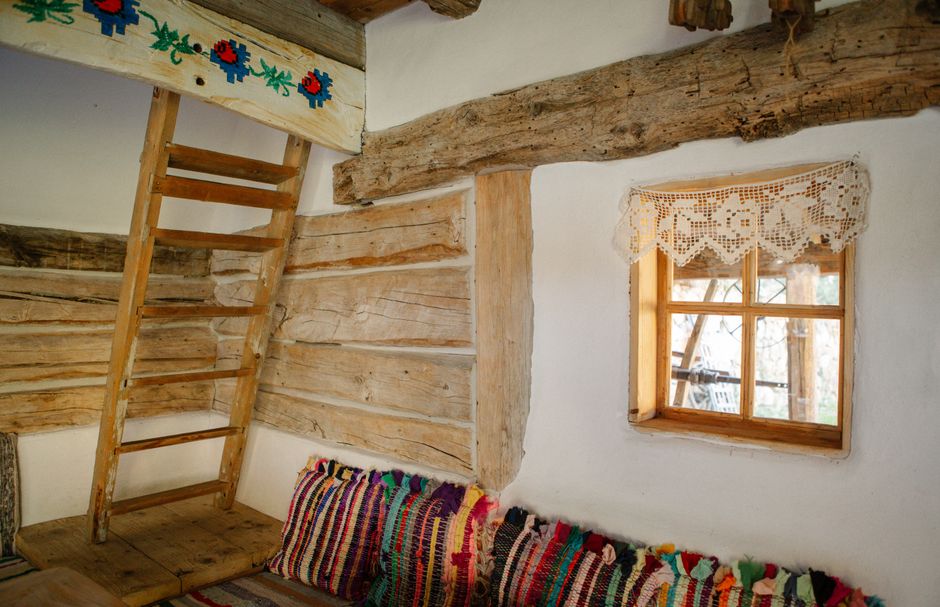 Rustic Romanian interior featuring wooden beams, woven textiles, and lace details.