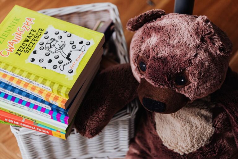 A stack of colorful children's books next to a plush teddy bear in a cozy kids' room.