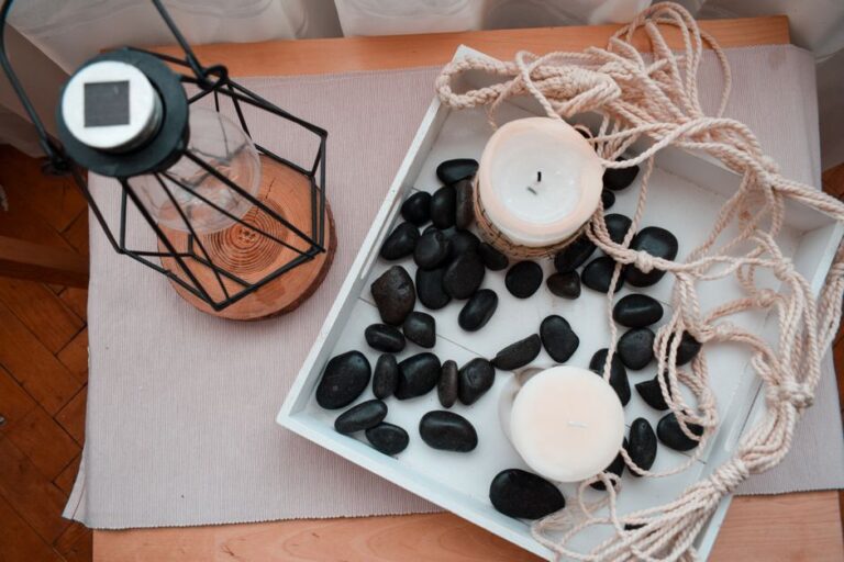 A warm, inviting scene featuring candles, stones, and a lantern on a wooden tray.